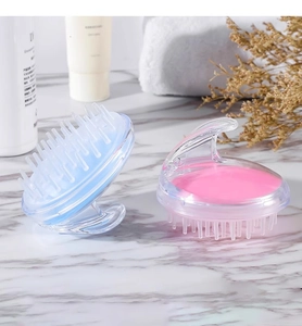 Close-up of blue and pink silicone scalp massager brushes on a marble bathroom counter