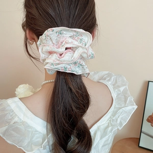 Detail of a floral chiffon scrunchie with pink flowers worn on a high ponytail
