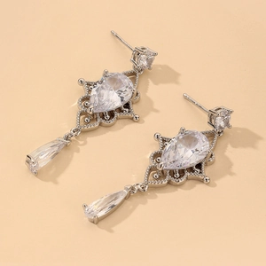 Macro shot of baroque style drop earrings with pear-cut cubic zirconia and silver lace detail