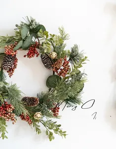 Detail of Christmas wreath with pine needles, red berries, pine cones and gold bells