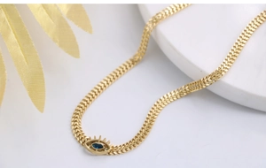 Detail of gold evil eye necklace with blue teardrop stone on marble tray