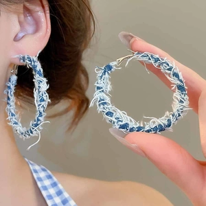 Detailed close-up of retro hoop earrings featuring frayed denim fabric and silver pins