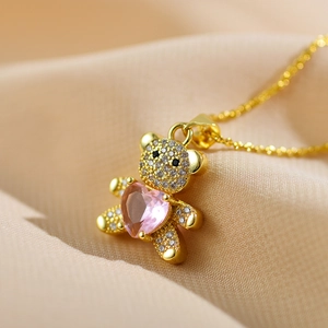 Macro detail of golden teddy bear pendant with micro-paved crystals and pink heart stone