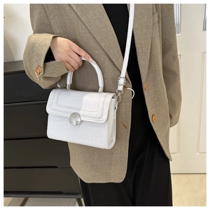 Detailed shot of white faux crocodile leather handbag with glossy finish and silver buckle