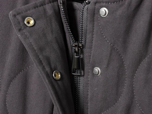 Detailed close-up of premium metal zipper and snap button on a black bomber jacket