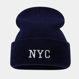 Gros plan sur la broderie blanche NYC d'un bonnet en maille bleu marine texturé