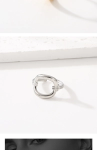 Detailed top view of a silver irregular hollow oval ring on white stone background