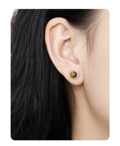 Detail of round sterling silver stud earring with brown tiger eye and pavé zircon stones