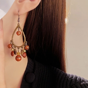 Detailed view of bohemian teardrop tassel earrings with copper metal and reddish beads