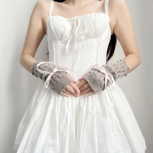 Close-up of knit arm sleeves with pink ribbon bows on soft grey-brown fabric