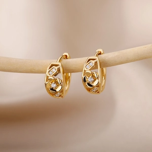 Macro detail of gold flower hoop earrings with white zircon on a natural branch