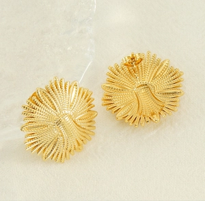 Macro detail of gold flower stud earrings showing front texture and back post