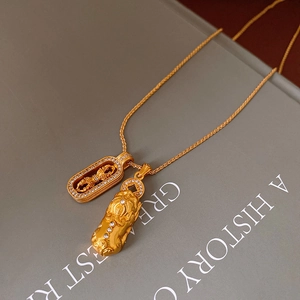 Detailed macro of gold plated Pixiu and Vajra pendants with sparkling cubic zirconia