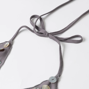 Dettaglio dell'abito grigio con scollo all'americana, decori a conchiglia e lacci