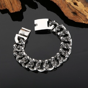 Detailed view of punk double-row skull chain bracelet in polished stainless steel on black