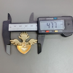 Detail showing the 47.7 mm measurement of the gold heart wing ring with a caliper