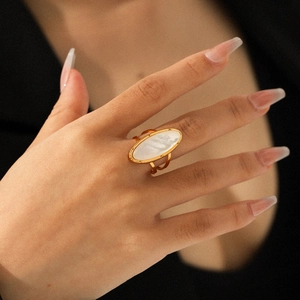 Anello in acciaio dorato con inserto ovale in madreperla bianca sulla mano