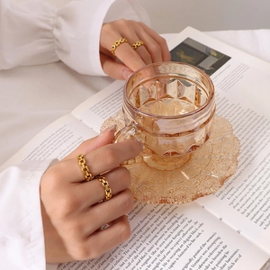 Minimalist gold plated hollow chain link ring set shown on model holding a glass