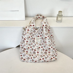 Detail of quilted white tote bag featuring cute cartoon prints and colorful logo patch
