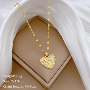 Close-up of gold heart pendant with flower motif and diamonds on beige jewelry box