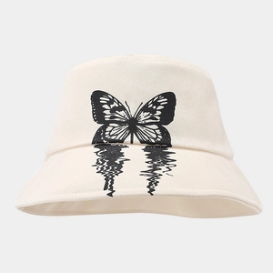 Detailed close-up of cream canvas bucket hat with artistic black butterfly print design