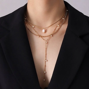 Chic layered gold Y-necklace with pearls, featuring a long tassel design on black suit