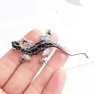 Macro view of lizard brooch with silver metal, black enamel patterns and clear rhinestones