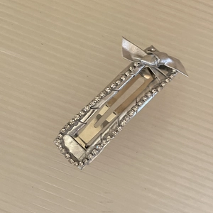 Dettaglio di un fermaglio per capelli argento con strass e decorazione a fiocco