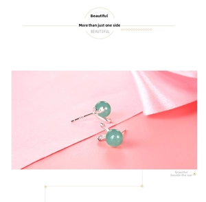 Close-up of S925 silver rabbit stud earrings with green agate beads on pink silk cloth