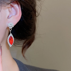 Detailed view of silver flower earrings with red diamond drop pendant on model