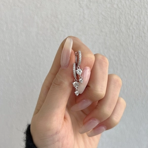 Macro shot of S925 sterling silver drop earrings with geometric zircons held by hand