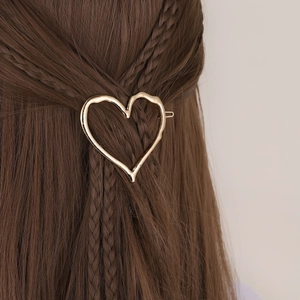 Golden irregular heart-shaped alloy hair clip with lava texture on dark braided hair