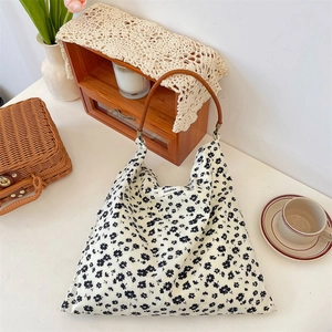 Détails d'un sac en toile à fleurs avec imprimés marguerites et poignées brunes