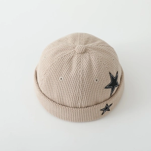 Detailed texture of corduroy brimless docker hat with embroidered black star patches