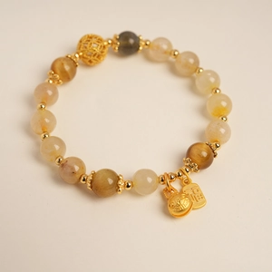 Détail du bracelet en citrine avec un pendentif Fu doré et une perle florale évidée