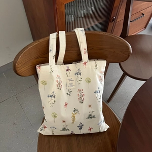 Floral canvas tote bag with vintage botanical prints hanging on a wooden chair
