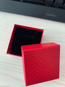 Detail view of a red jewelry gift box featuring elegant diamond pattern and black velvet insert