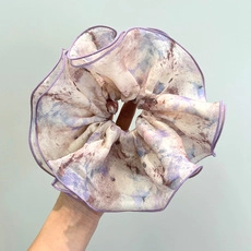 Detail view of purple and beige tie-dye organza hair scrunchie with soft ruffled texture