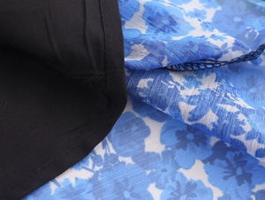 Close-up of blue floral chiffon fabric and black lining detail on an elegant long dress
