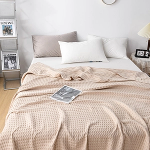 Detailed close-up of cream waffle weave cotton blanket texture and hem stitching quality
