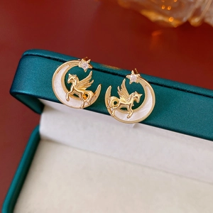 Macro shot of vintage golden pegasus and crescent moon stud earrings with zircon stars