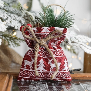 Red Christmas jute gift bag with reindeer print on a festive snowy wooden background