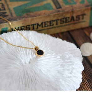 Detailed macro view of a 18K gold plated necklace with a black shell pendant and beaded edge