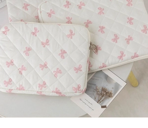 Detailed close-up of quilted laptop sleeves with pink bow patterns and round zippers