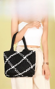 Detail view of oversized woven tote bag in black and white geometric pattern on model