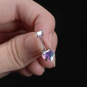 Rainbow heart-shaped belly button ring in surgical steel held by hand against black background