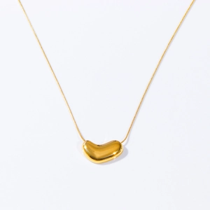 Macro detail of the 18k gold plated heart bean pendant on a sleek snake chain necklace