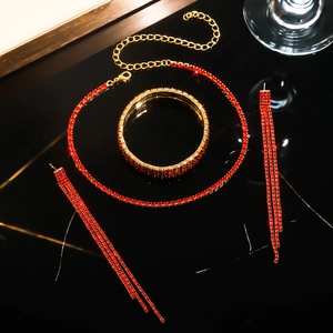 Close-up of red rhinestone necklace and tassel earrings on a reflective black base
