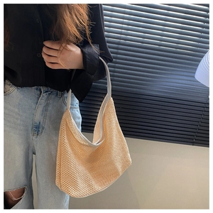 Detailed view of beige woven shoulder bag with mesh texture on a model shoulder