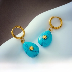 Detailed close-up of retro teardrop turquoise earrings with gold floral accents